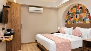 Quarto de hotel com cama, mesa de cabeceira, guarda-roupa e ar condicionado.