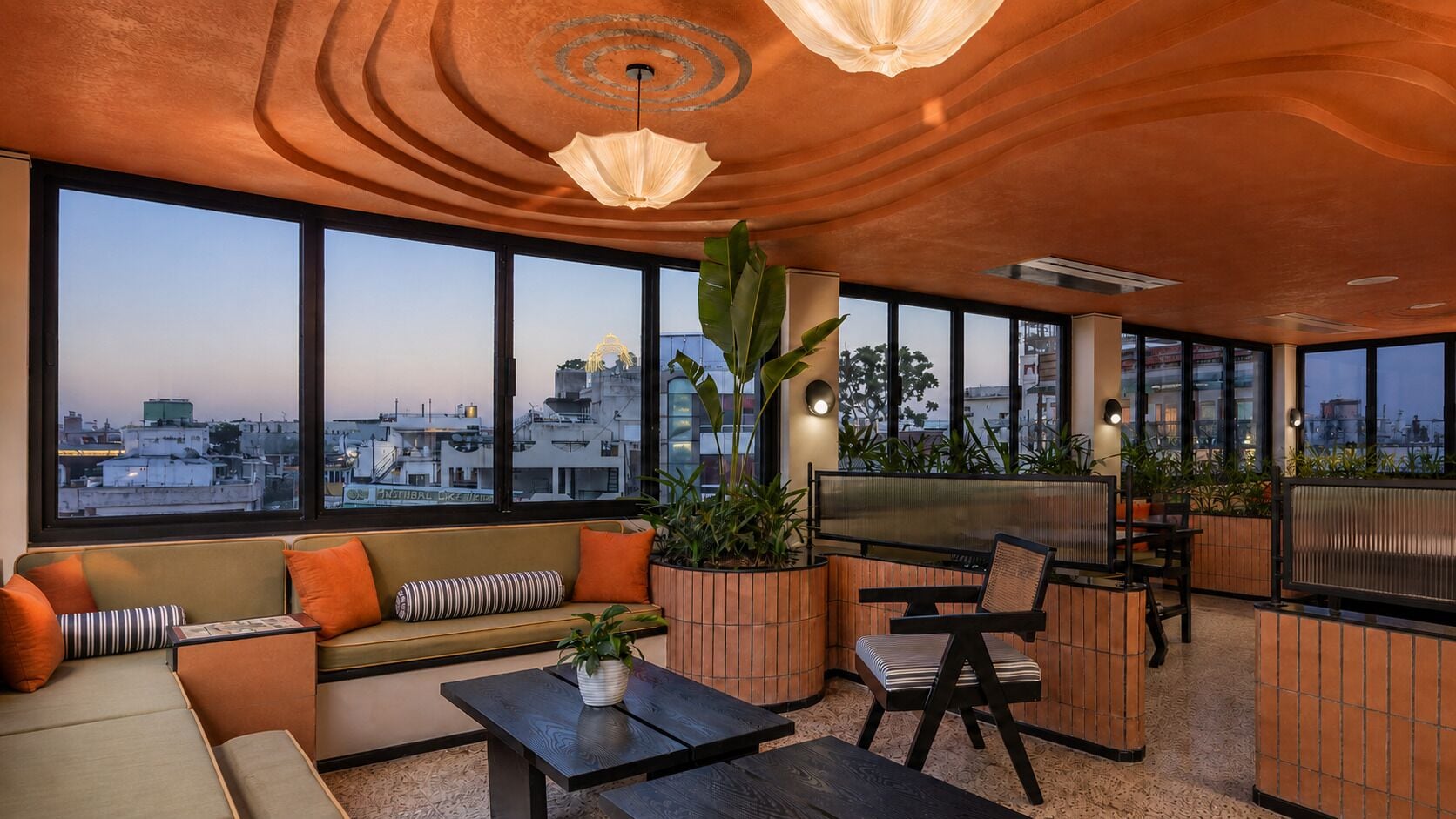 A modern lounge area with a sofa, chairs, a coffee table, and a large window offering a city view.