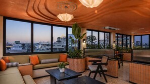 Uma área de estar moderna com sofá, cadeiras, mesa de centro e uma janela grande com vista para a cidade.