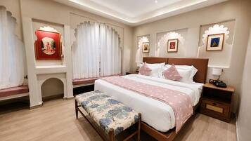 A hotel room with a large bed, a bench, a nightstand, and a wall-mounted shelf with a framed picture.
