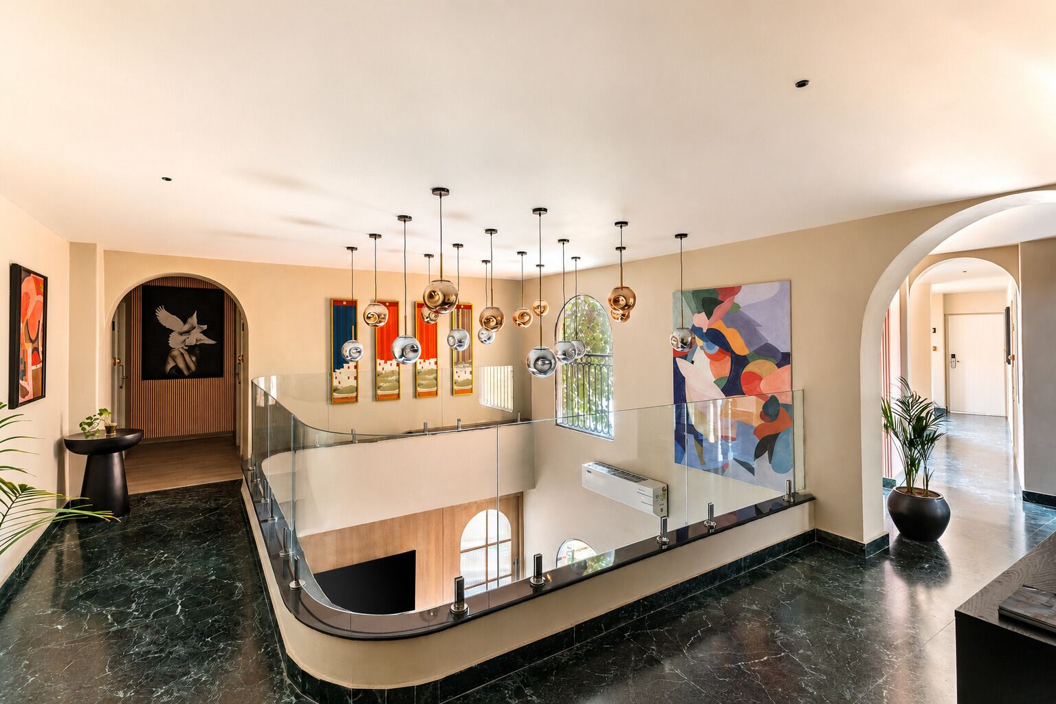 A modern lobby with a glass railing, artwork on the walls, and a central staircase.