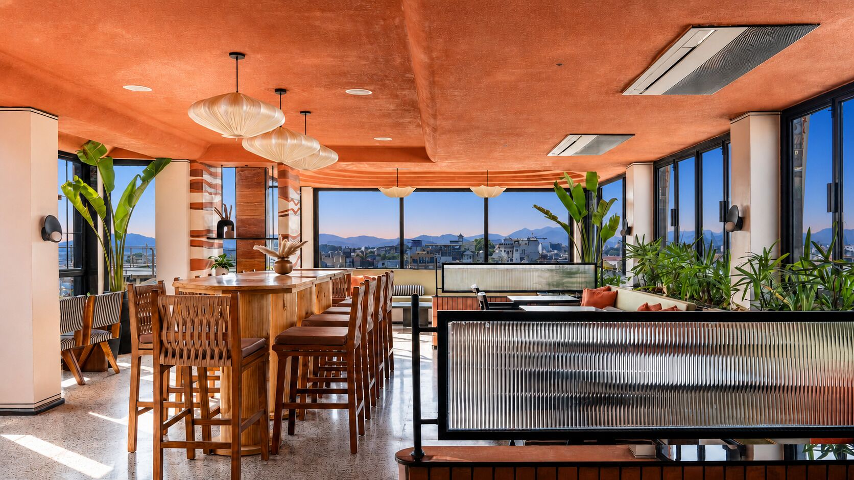 A spacious bar area with wooden furniture and large windows offering a city view.