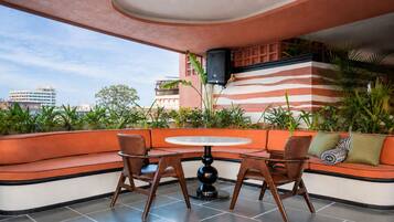 A seating area with a round table and chairs, surrounded by a cushioned bench with pillows.