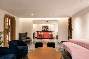 A modern interior with a seating area, a bar, and a bookshelf. - My Downtown - The Red Pier (Udaipur)