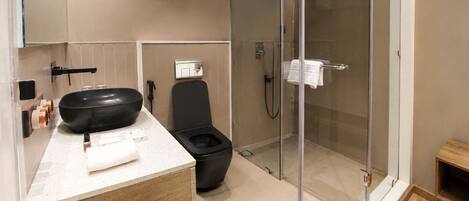 A modern bathroom with a black bathtub, a toilet, and a glass-enclosed shower area.