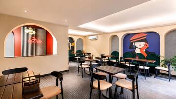 Interior de restaurante con mesas, sillas, un letrero de neón y un mural en la pared.