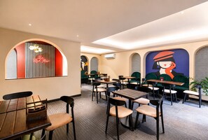 Interior de restaurante con mesas, sillas, un letrero de neón y un mural en la pared.