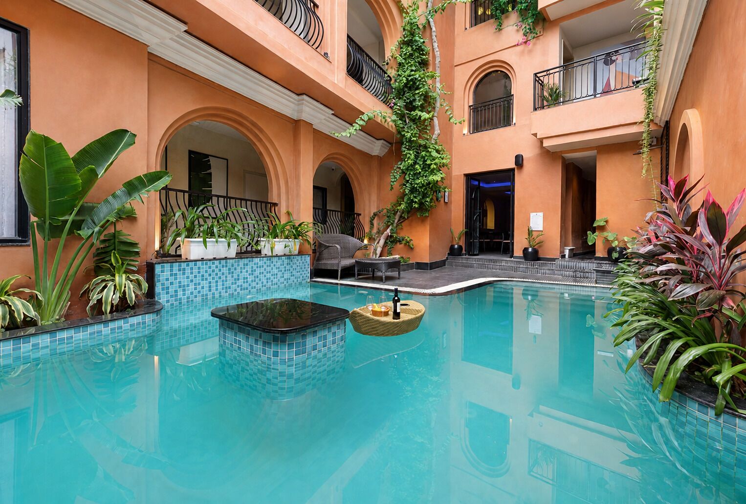 A pool area with a tiled floor, lounge chairs, and potted plants.