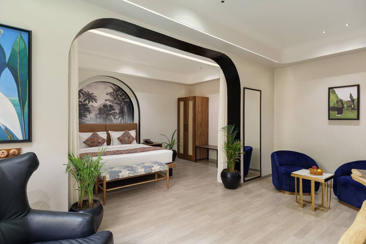 A modern hotel room with a bed, seating area, and a large mirror.
