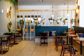 A restaurant with wooden furniture, a blue sofa, and hanging plants. - Tulip Inn Campos de Goytacazes (Campos)