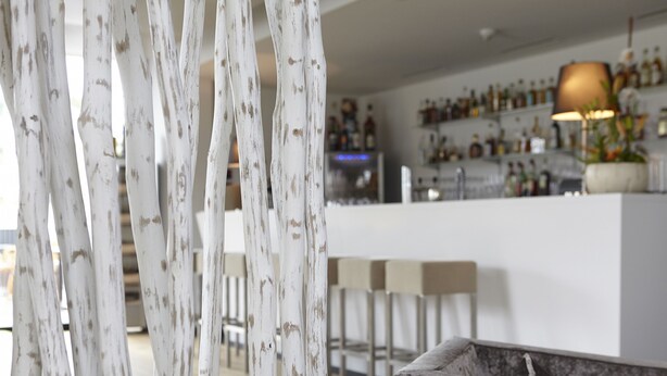 Un área de bar moderna con mostrador blanco y taburetes.