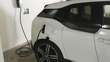 A white car parked indoors, connected to a charging station.