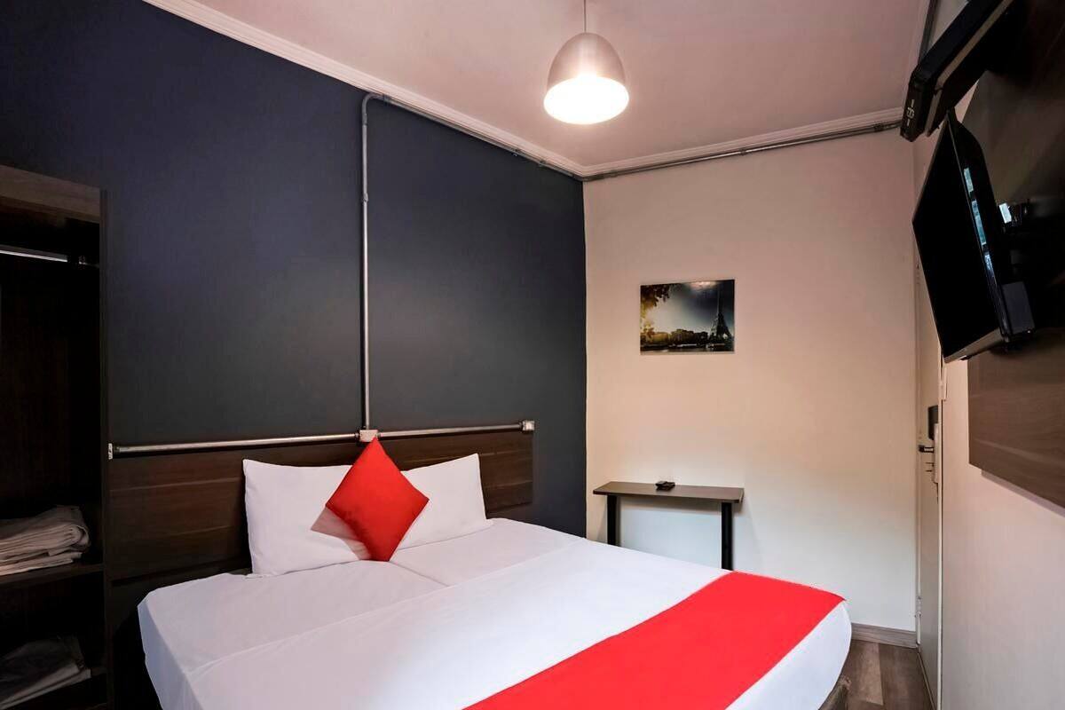 A hotel room with a bed, a bedside table, a TV, and a wardrobe.