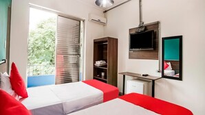 Una habitación de hotel con dos camas, televisión, armario y un pequeño escritorio.
