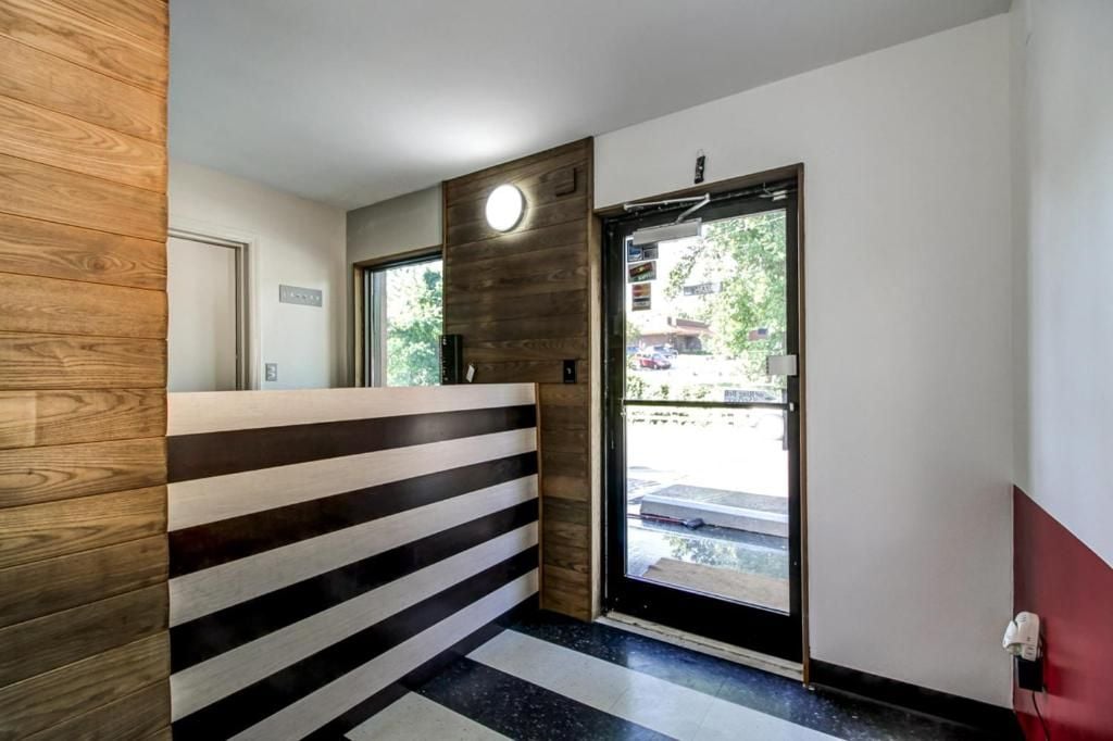 A reception area with a wooden reception desk, a black and white striped wall, and a door leading outside.