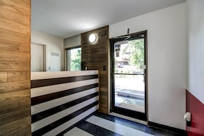 A reception area with a wooden reception desk, a black and white striped wall, and a door leading outside. - The Asheville Inn (Asheville)