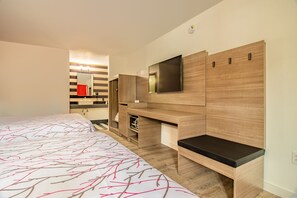 A modern hotel room with a large bed, a TV mounted on the wall, and built-in storage units.
