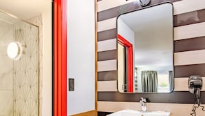 Ein modernes Badezimmer mit einem weißen Waschbecken, einem beleuchteten Spiegel und einer gestreiften Wand.