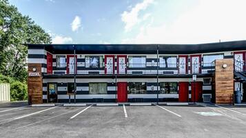 A two-story building with numbered doors, a staircase, and a parking lot.