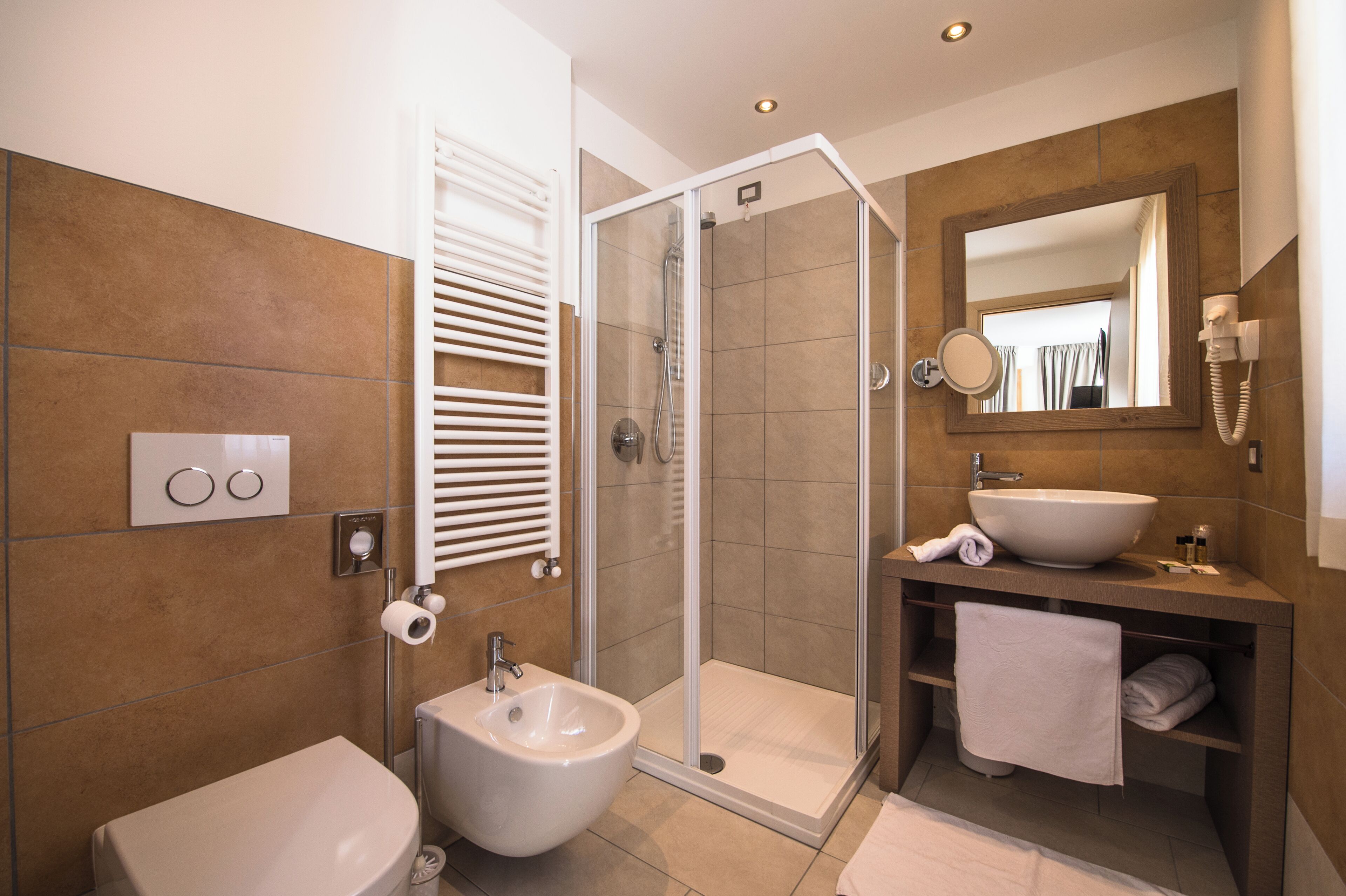 A modern bathroom with a shower, bidet, sink, and toilet.