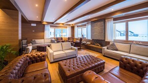 A spacious living area with leather sofas, a fireplace, and large windows offering a view.