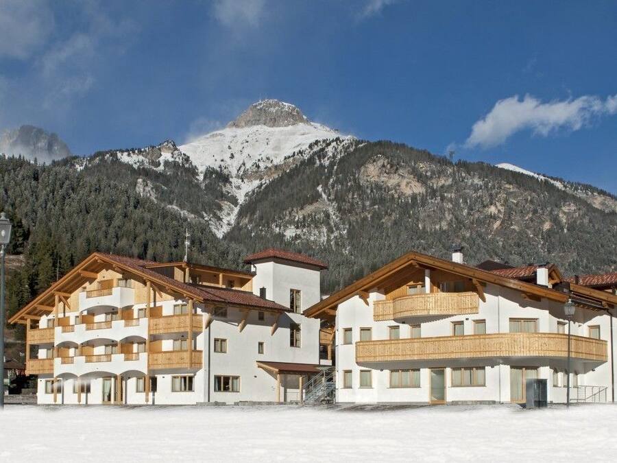 A hotel with multiple floors, balconies, and a view of snow-covered mountains.