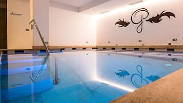 A swimming pool with a glass barrier, a shower area, and a wall with a logo.