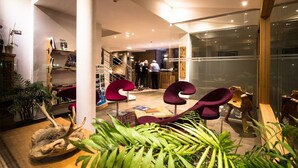 A modern interior with a staircase, seating area, and glass walls.