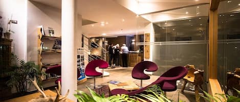 A modern interior with a staircase, seating area, and glass walls.