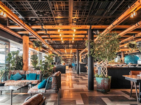 A spacious indoor area with wooden beams, hanging plants, and a central bar area.. Novotel Istanbul Bosphorus