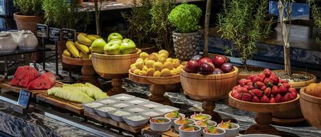 A fruit and yogurt display with various fruits and bowls of yogurt.