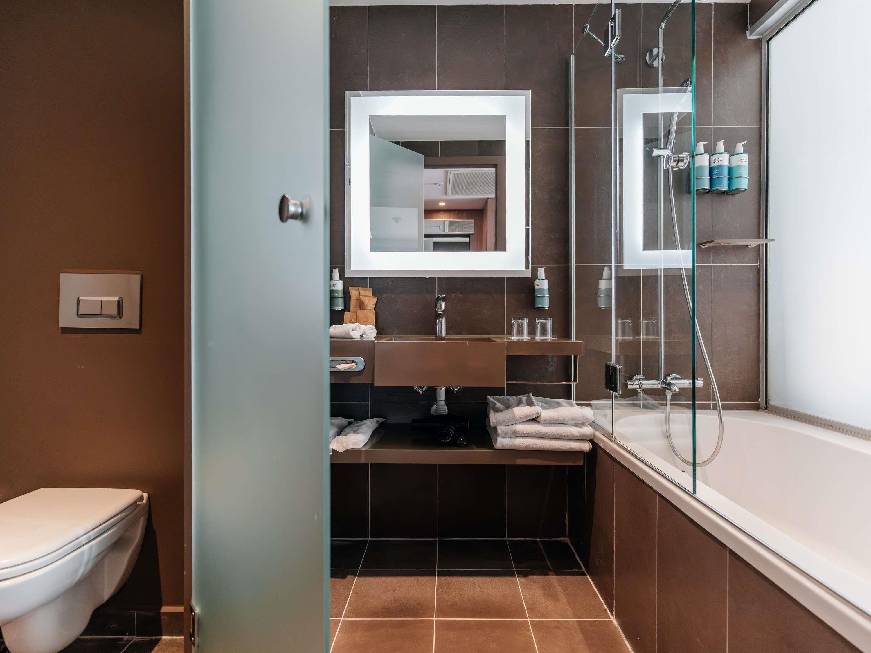 A modern bathroom with a toilet, a sink with a mirror, a shower area, and a glass-enclosed shower.