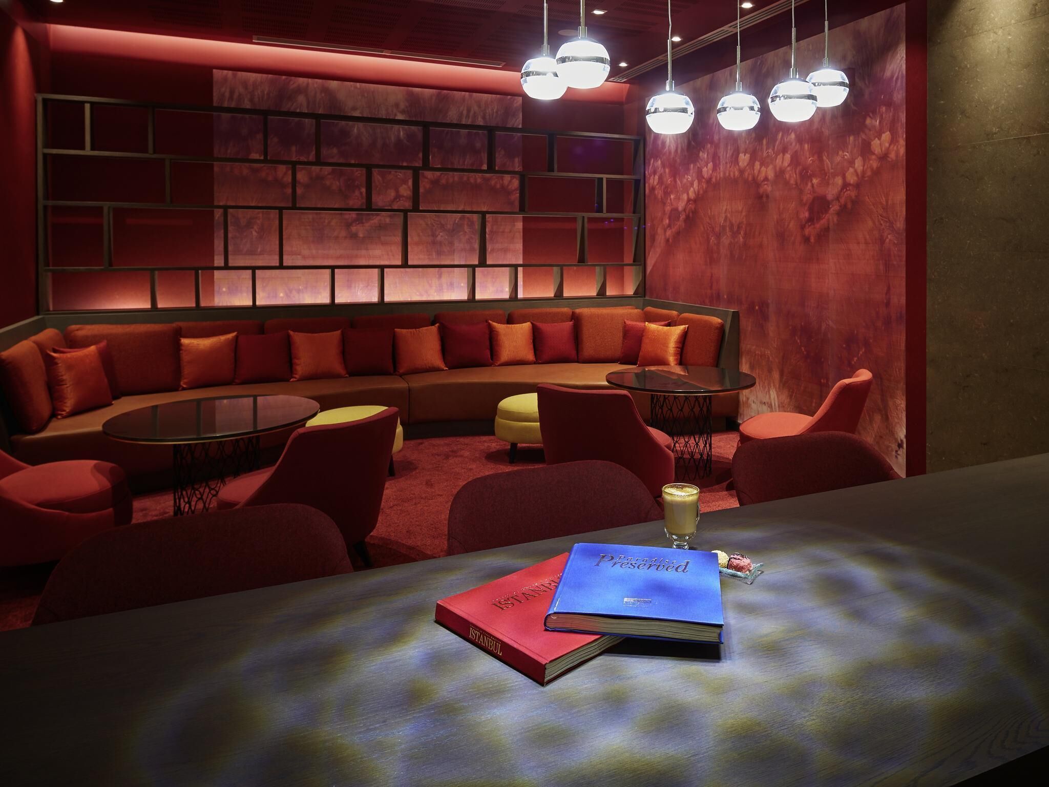 A modern lounge with a curved sofa, round tables, and a book titled 'ISTANBUL' on the table.