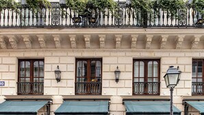 A building with a balcony, outdoor seating, and potted plants. - Hôtel Providence (Paris)