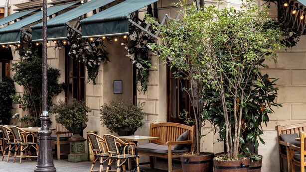 A building with outdoor seating, potted plants, and a green awning. - Hôtel Providence (Paris)
