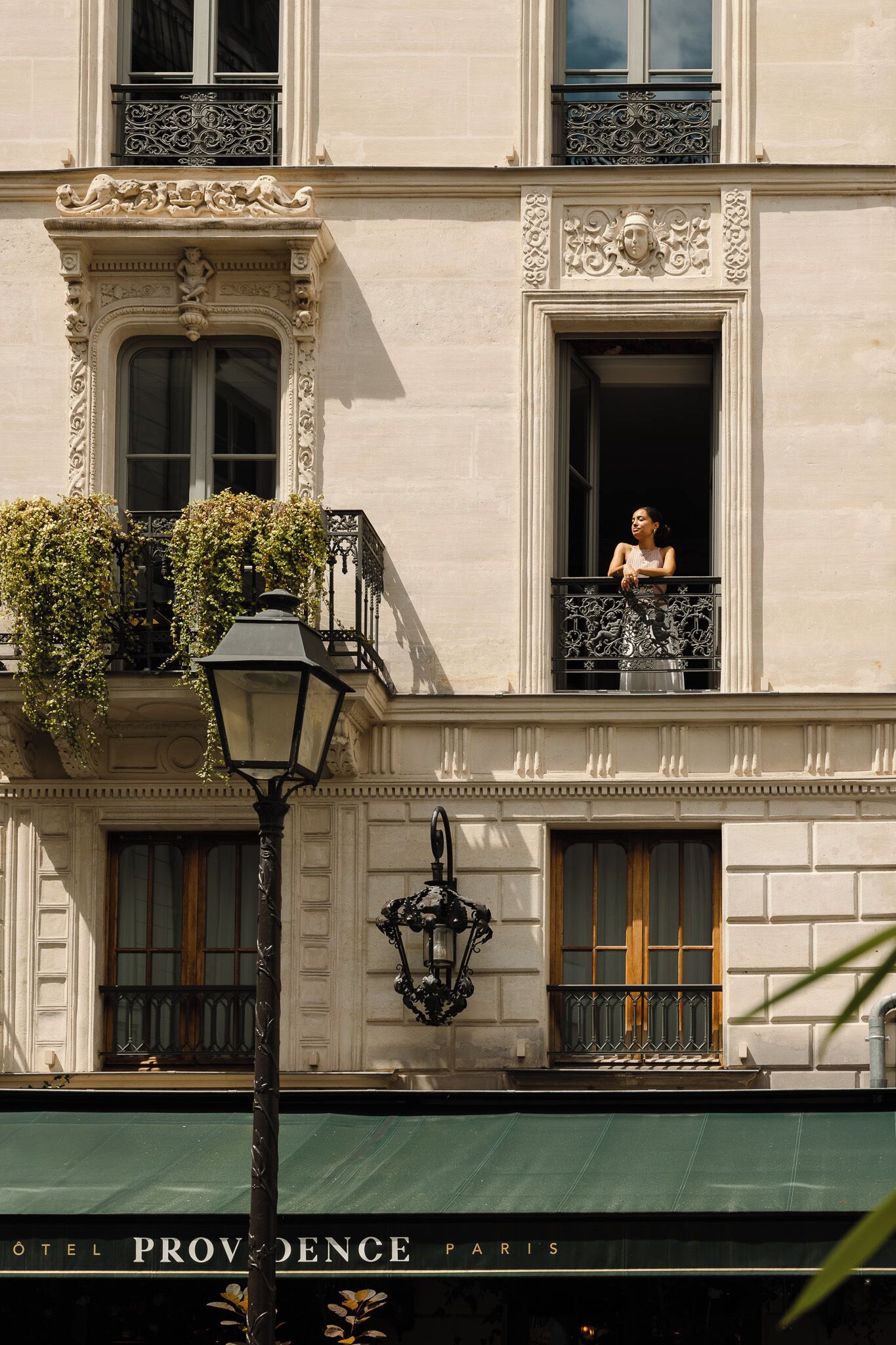 A building with ornate architectural details, including a balcony with plants and a sign reading "Hotel Provence Paris".