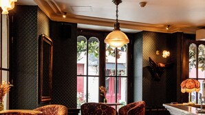 A bar area with patterned chairs, a wooden cabinet, and a hanging light fixture. - Hôtel Providence (Paris)