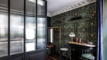A room with a large window, a mirror, a bar area with stools, and a patterned wall.