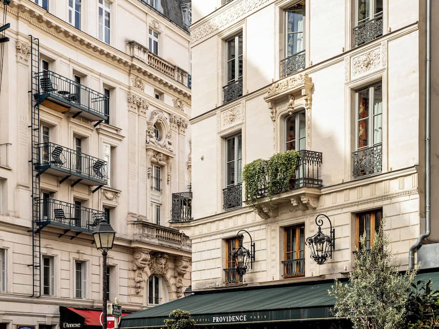 A historic building with ornate balconies, a green awning, and a sign for "Providence Paris".