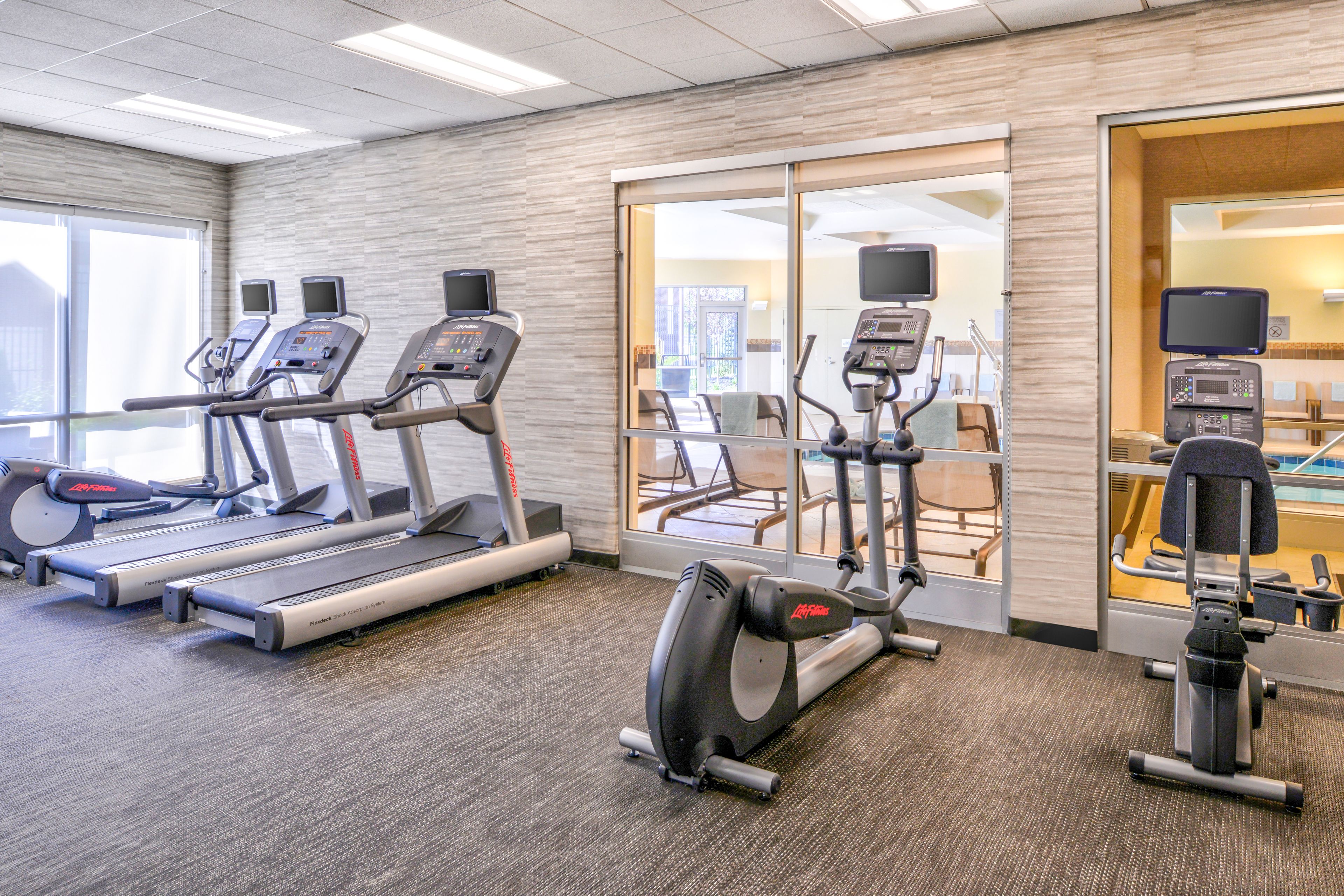 Een fitnessruimte met loopbanden, elliptische trainers en hometrainers.