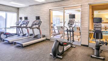 Een fitnessruimte met loopbanden, elliptische trainers en hometrainers.