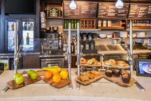 Mostrador de panadería con frutas frescas, muffins y pasteles.
