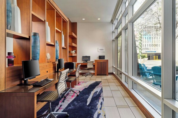 Un espacio de oficina moderno con escritorio, computadora y silla, un ventanal grande y un letrero que indica un garaje central.