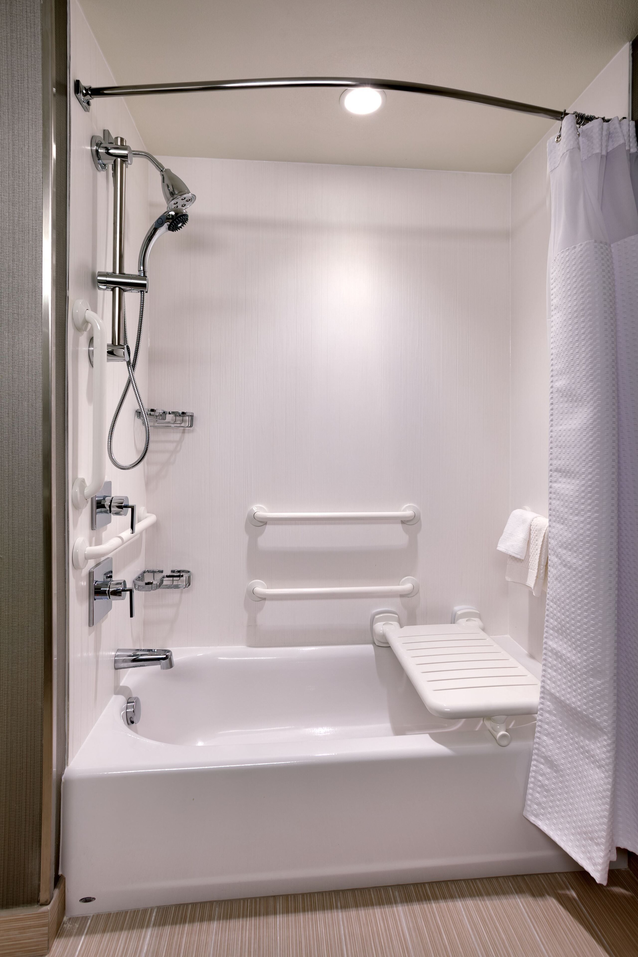 Un baño moderno con bañera, ducha y barras de apoyo.