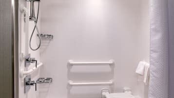 Un baño moderno con bañera, ducha y barras de apoyo.