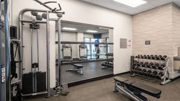 A gym with weight machines, dumbbells, and a bench.