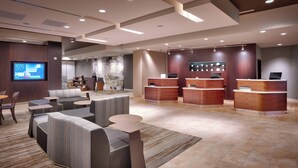 A modern hotel lobby with a reception desk, seating area, and a large screen displaying information. - Courtyard Salt Lake City Downtown (Salt Lake City)