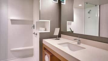 A modern bathroom with a large mirror, a sink, and a shower.