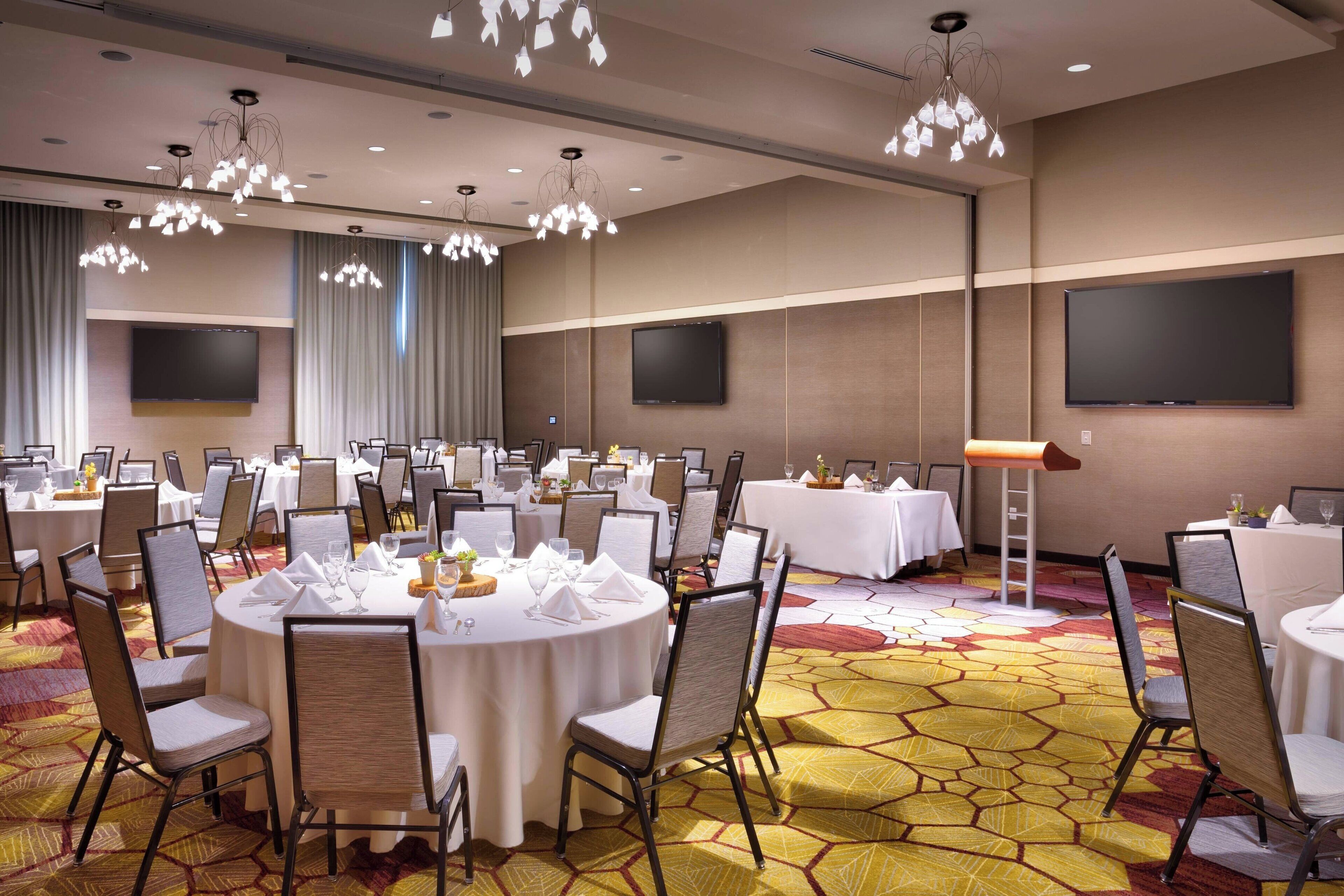 A conference room with round tables, chairs, and a carpeted floor.