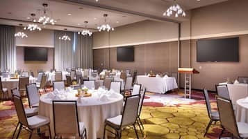 A conference room with round tables, chairs, and a carpeted floor.